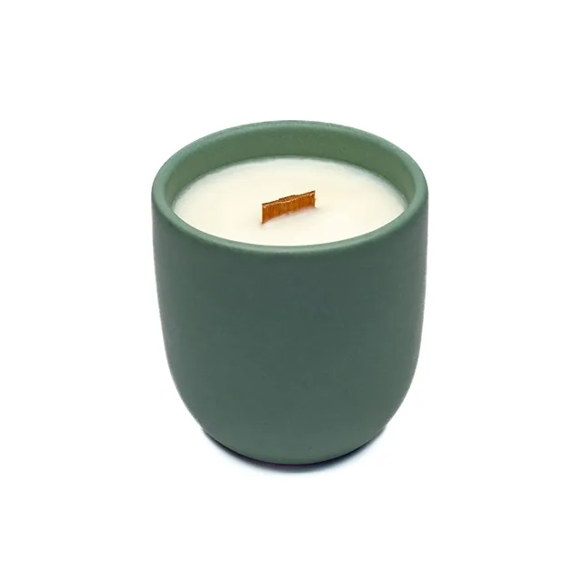 A natural scented candle in a hunter green matt ceramic vessel, custom-made for the product line of a European brand